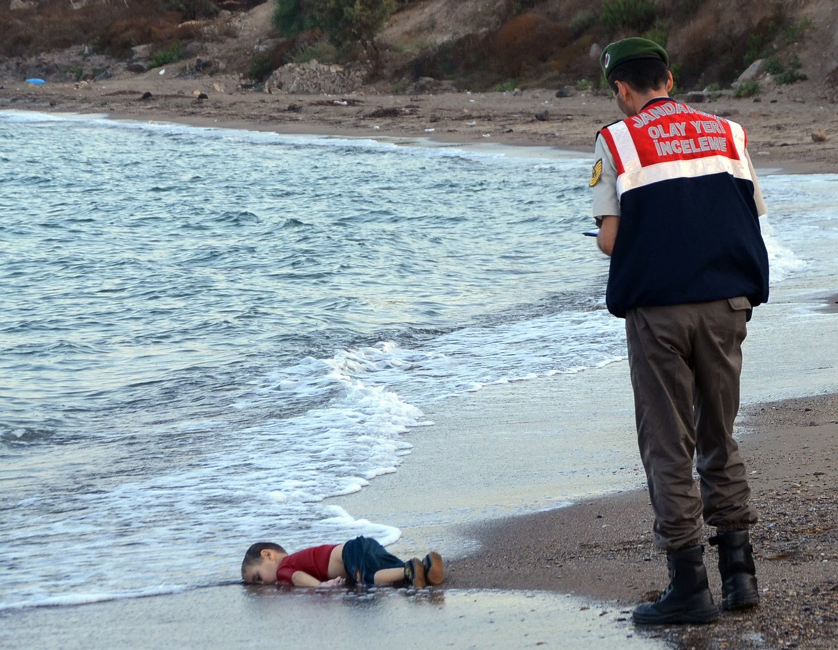 ضابط شرطة تركي يقف على جثة الطفل الغريق آلان كردي الذي لفظته أمواج البحر على شواطئ (بودروم) جنوب تركيا.