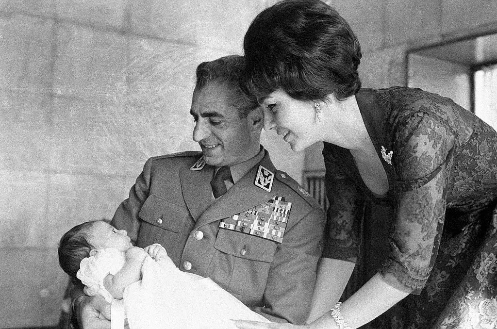 صورة تجمع الشاه وهو يرتدي الزي العسكري ويجلس على ركبتيه أمام ابنه المولود حديثا (رضا بهلوي الثاني) وزوجته (فرح ديبا) في ديسمبر 1960. صورة: Jack Garofalo/Paris Match/Getty Images